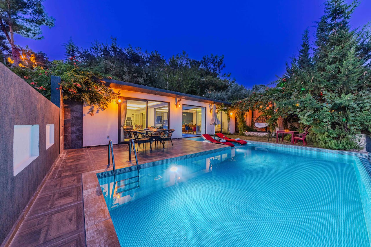 Elegant modern villa with a swimming pool surrounded by lush greenery in the evening.
